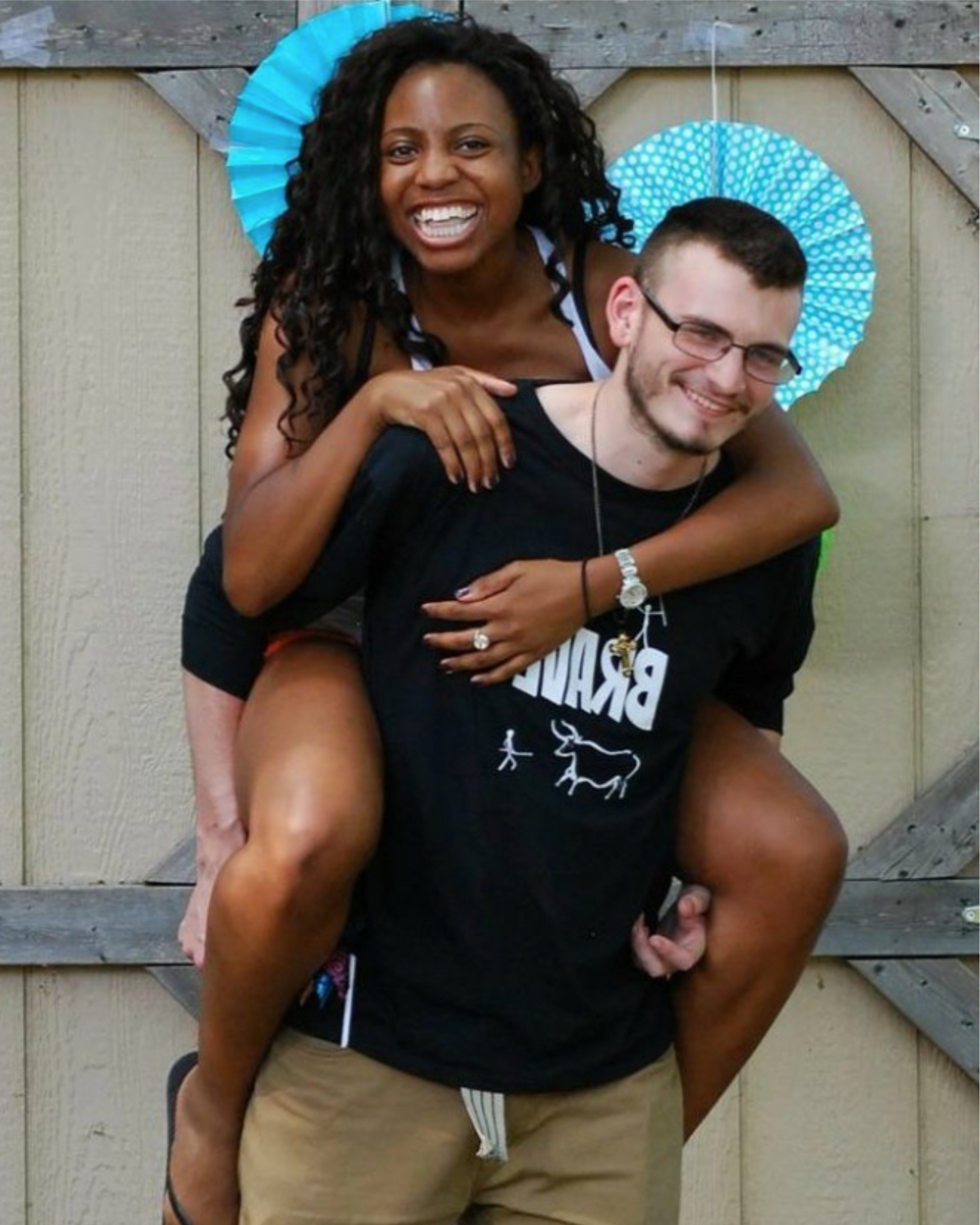 TaCora and Alexander Backstrom posing together with a wooden background wearing their apparel line.